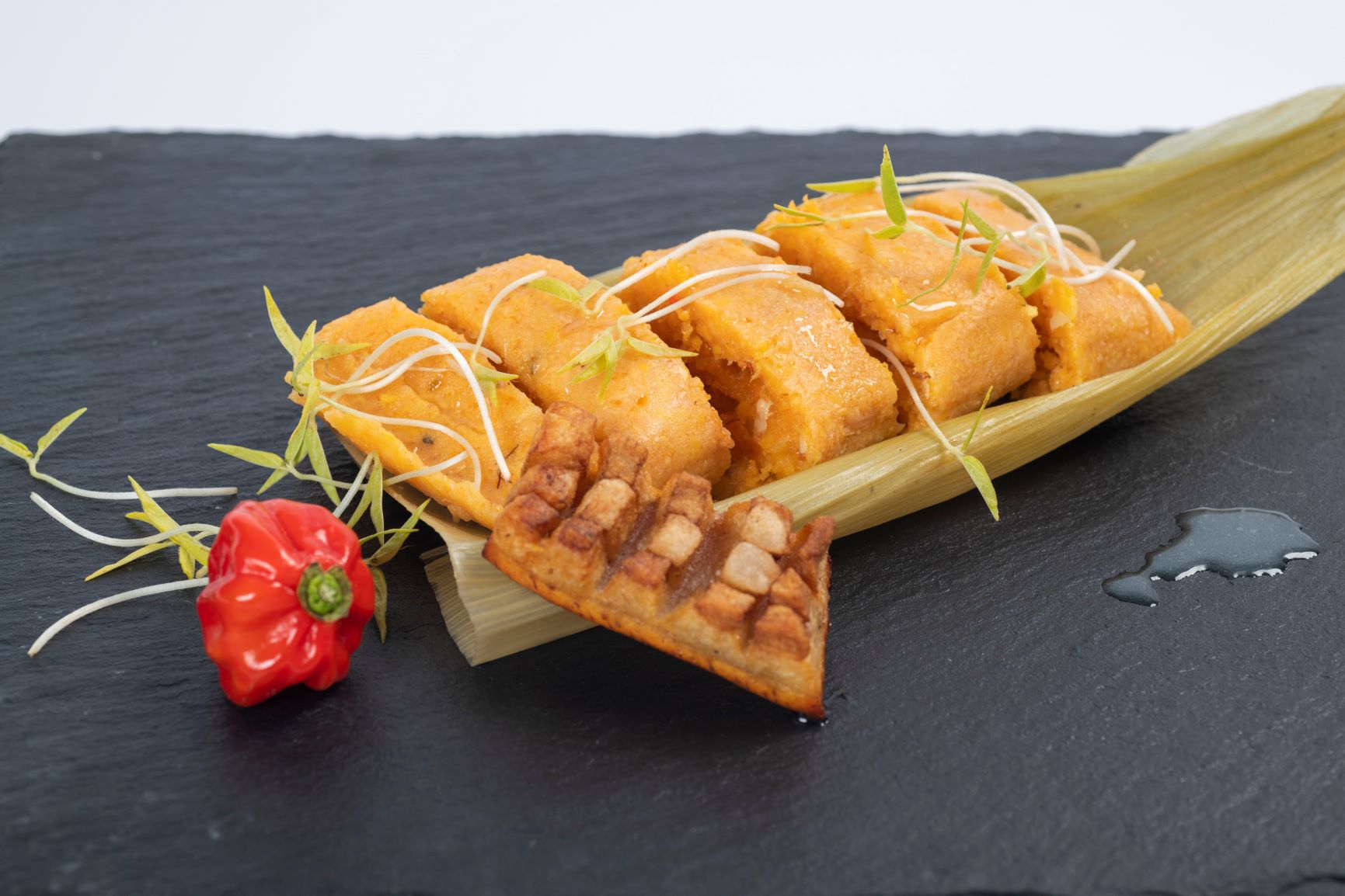 Entre los ingredientes más importantes se encuentran el maíz, el cerdo, el ajo, la cebolla y las especias como el comino y el orégano.