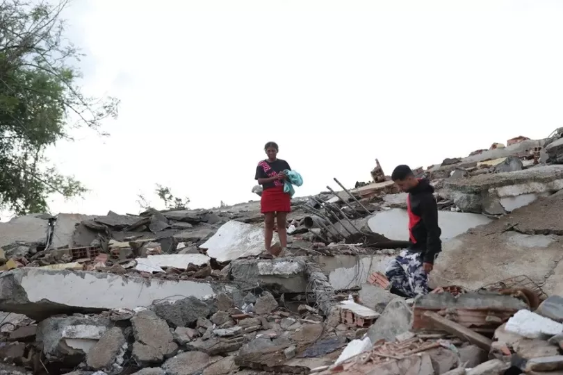 Personas utilizando sus teléfonos móviles para buscar información sobre víctimas del terremoto en Venezuela a través de redes sociales.