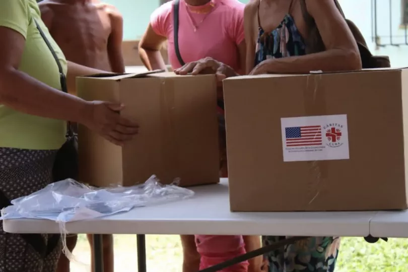 Paquetes de ayuda humanitaria con la bandera de Estados Unidos y el logotipo de Cáritas Cuba durante su entrega.