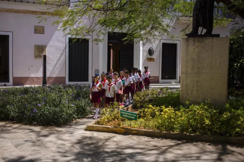 Estudiantes cubanos frente a una escuela, representando el sistema educativo.