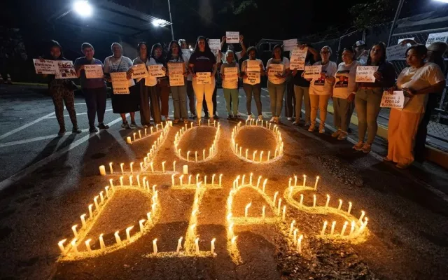 Familiares de presos políticos venezolanos sostienen pancartas durante una vigilia de 100 días frente a una cárcel.