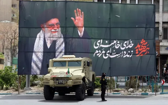 Un miembro de las fuerzas de seguridad iraníes monta guardia junto a una pancarta en honor al exlíder supremo iraní Ali Khamenei en Teherán.