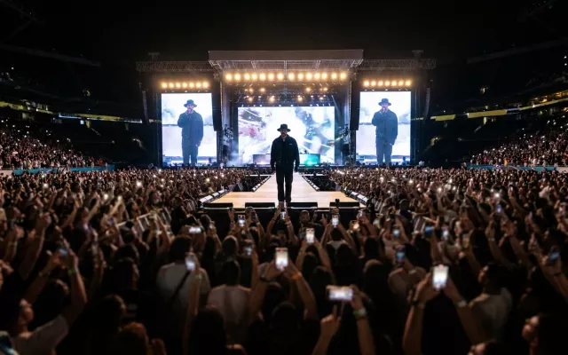 El artista Bad Bunny actuando ante una multitud en un estadio.