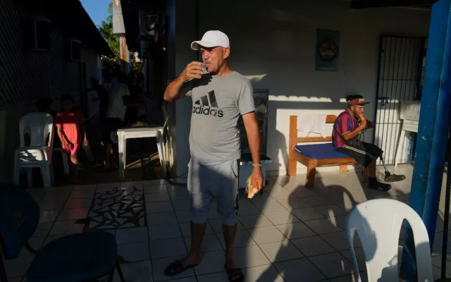 Miguel Hidalgo, un migrante cubano, toma un vaso de leche para desayunar en un albergue en Rio Branco, Brasil 