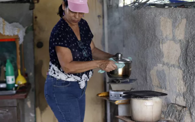 Persona cocinando con carbón ante la falta de electricidad.
