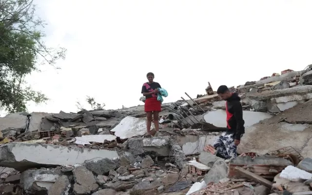 Personas utilizando sus teléfonos móviles para buscar información sobre víctimas del terremoto en Venezuela a través de redes sociales.