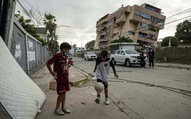 Niños juegan fútbol frente a un edificio afectado por un terremoto, el 27 de junio de 2026, en La Guaira (Venezuela). 