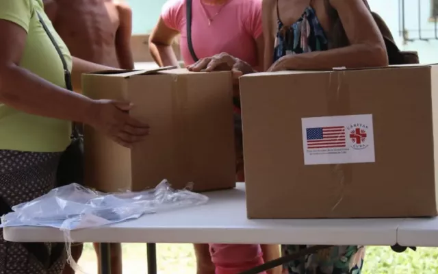 Paquetes de ayuda humanitaria con la bandera de Estados Unidos y el logotipo de Cáritas Cuba durante su entrega.