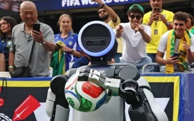 El robot humanoide Atlas realizando una pose de celebración de gol en un estadio de fútbol.