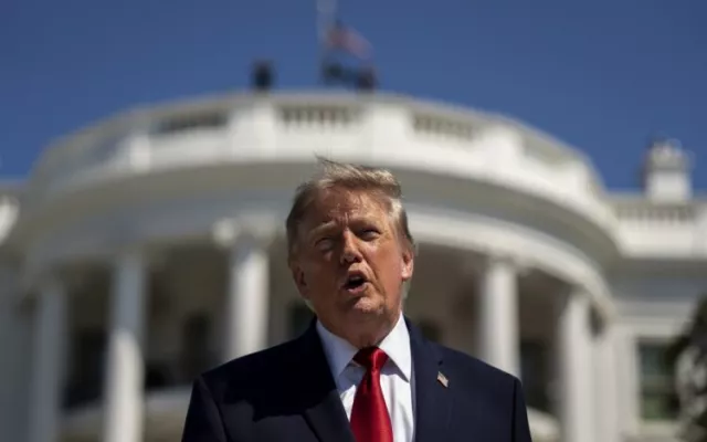 El presidente, de EE.UU, Donald Trump, habla con la Casa Blanca de fondo.