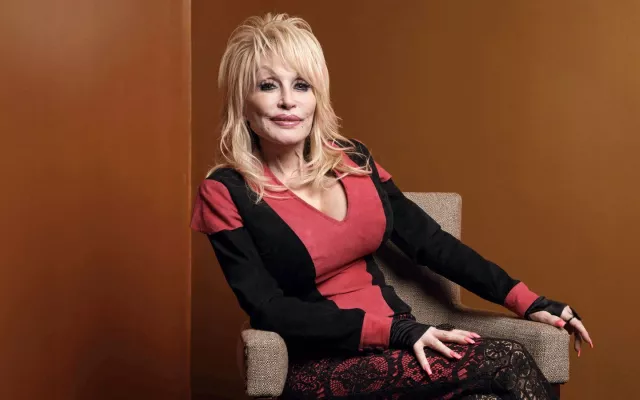 Fotografía de archivo de Dolly Parton sonriendo con su característico estilo.