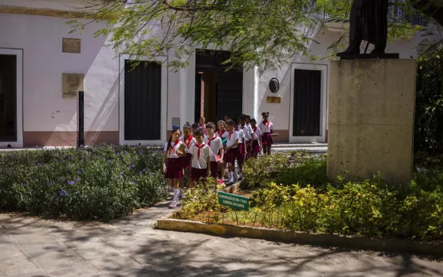 Estudiantes cubanos frente a una escuela, representando el sistema educativo.