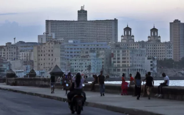 Personas caminando por el malecón durante una jornada de apagón.