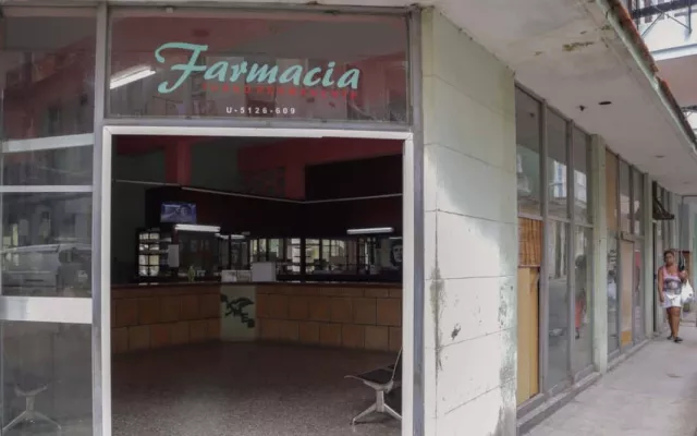 Vista exterior de una farmacia en Cuba con letreros informativos sobre la disponibilidad de medicamentos.