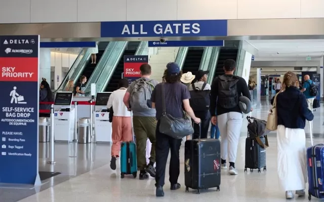 Punto de control de seguridad en un aeropuerto estadounidense donde se observa personal de la TSA y viajeros.