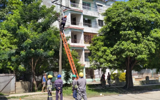 Personal eléctrico trabajando en condiciones de riesgo cerca de una estructura de red.
