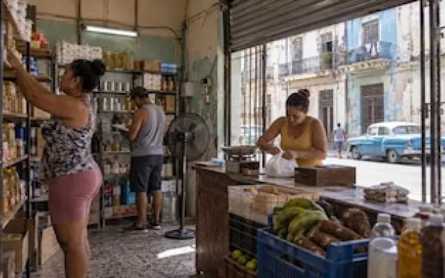 Mostrador de un mercado de barrio con estantes parcialmente abastecidos y pizarra de precios en Cuba.